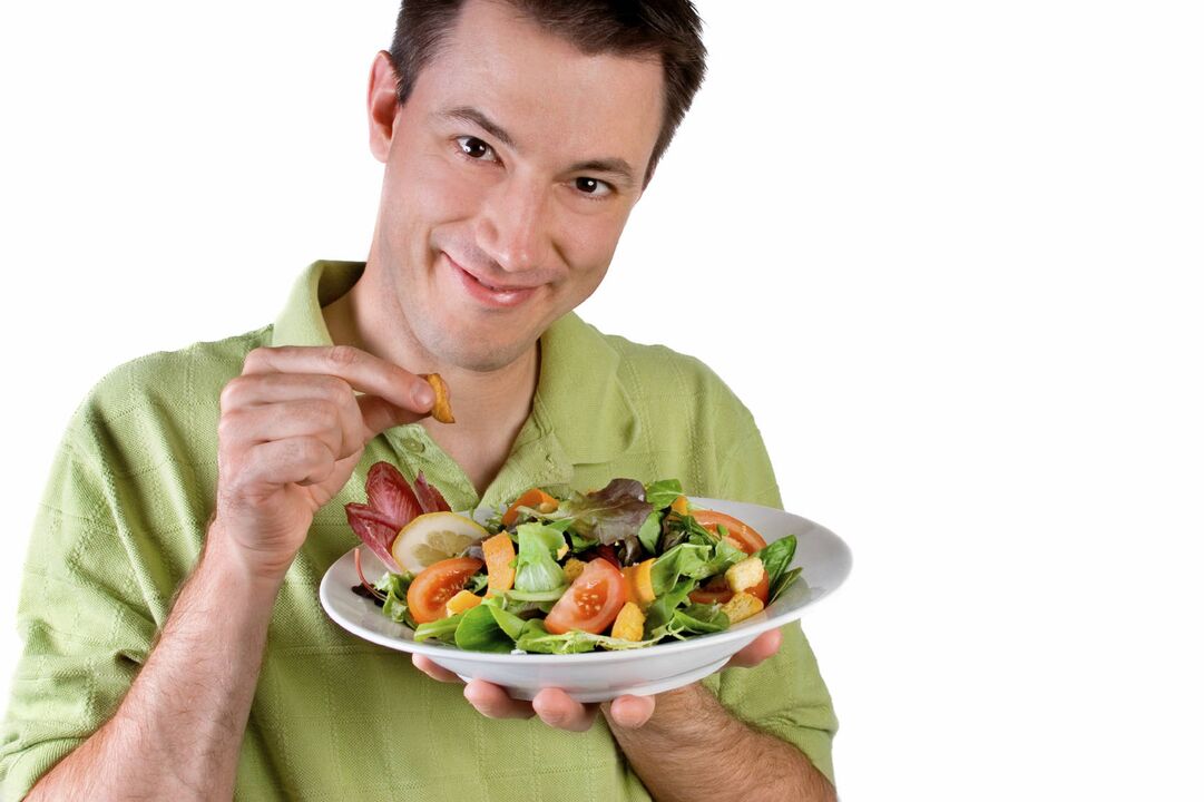 L'uomo mangia insalata di verdure per aumentare la potenza